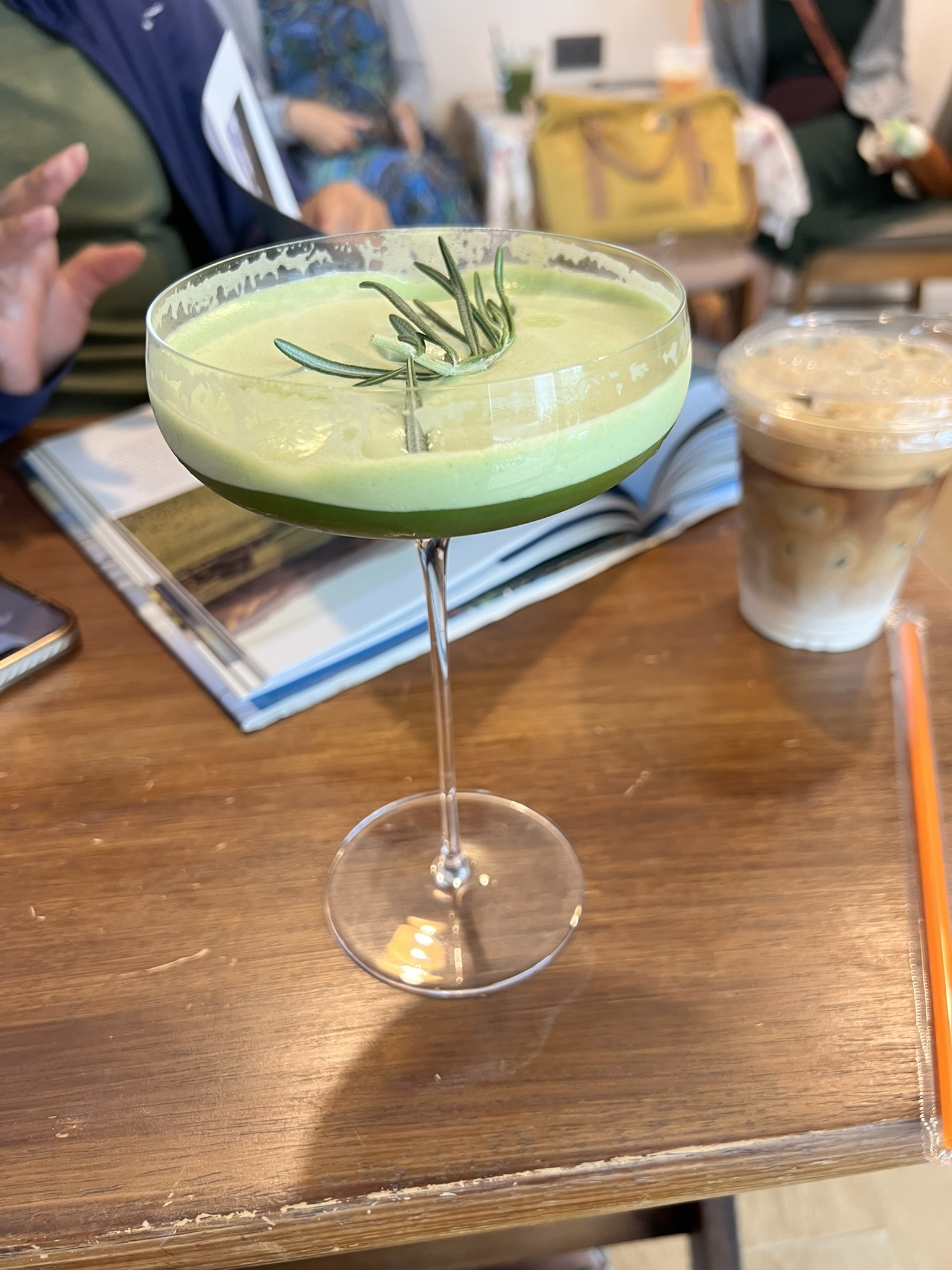 A bright green cafe drink shared at a table with friends