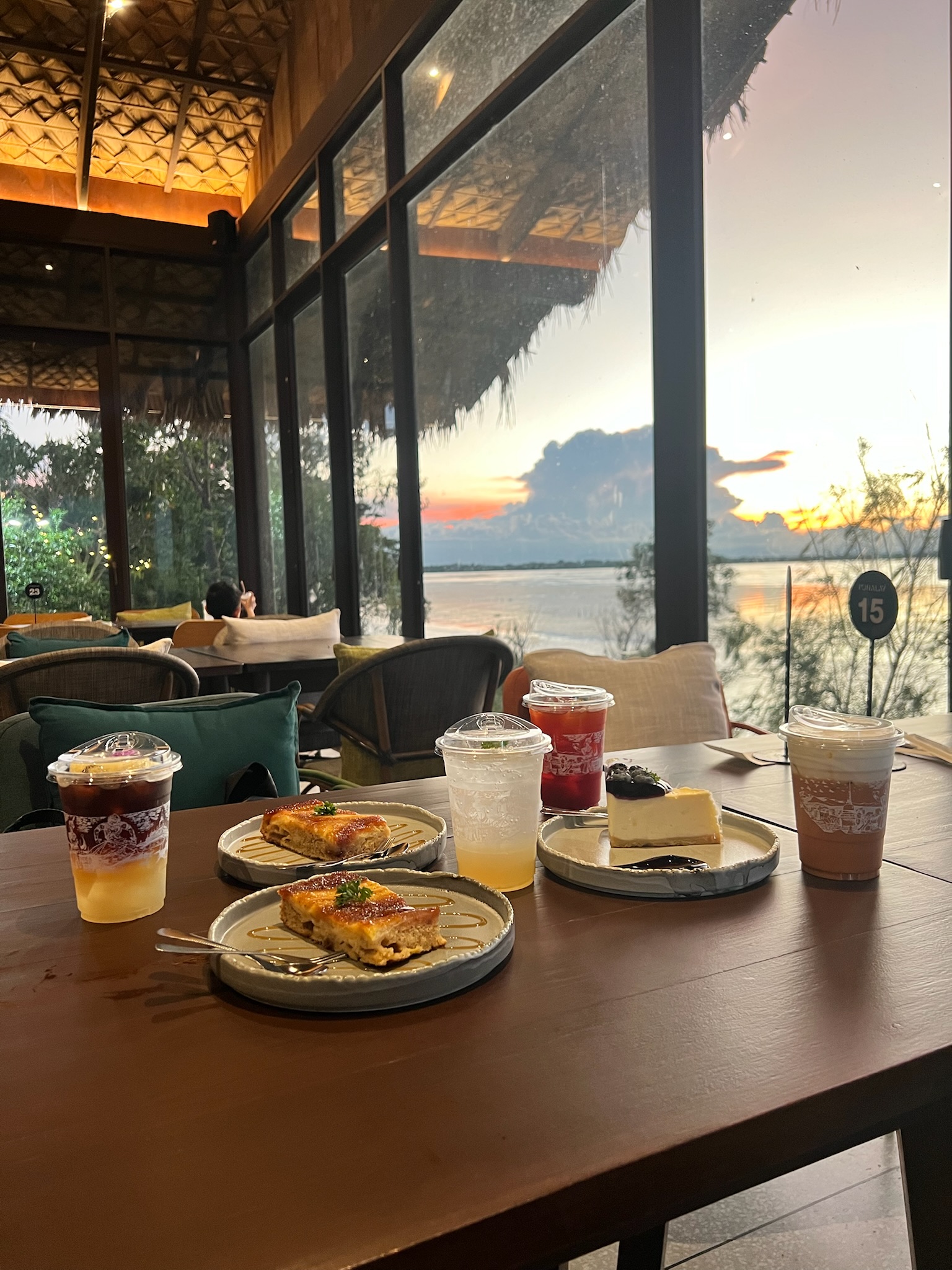 Desserts and drinks at a lakeside cafe during sunset