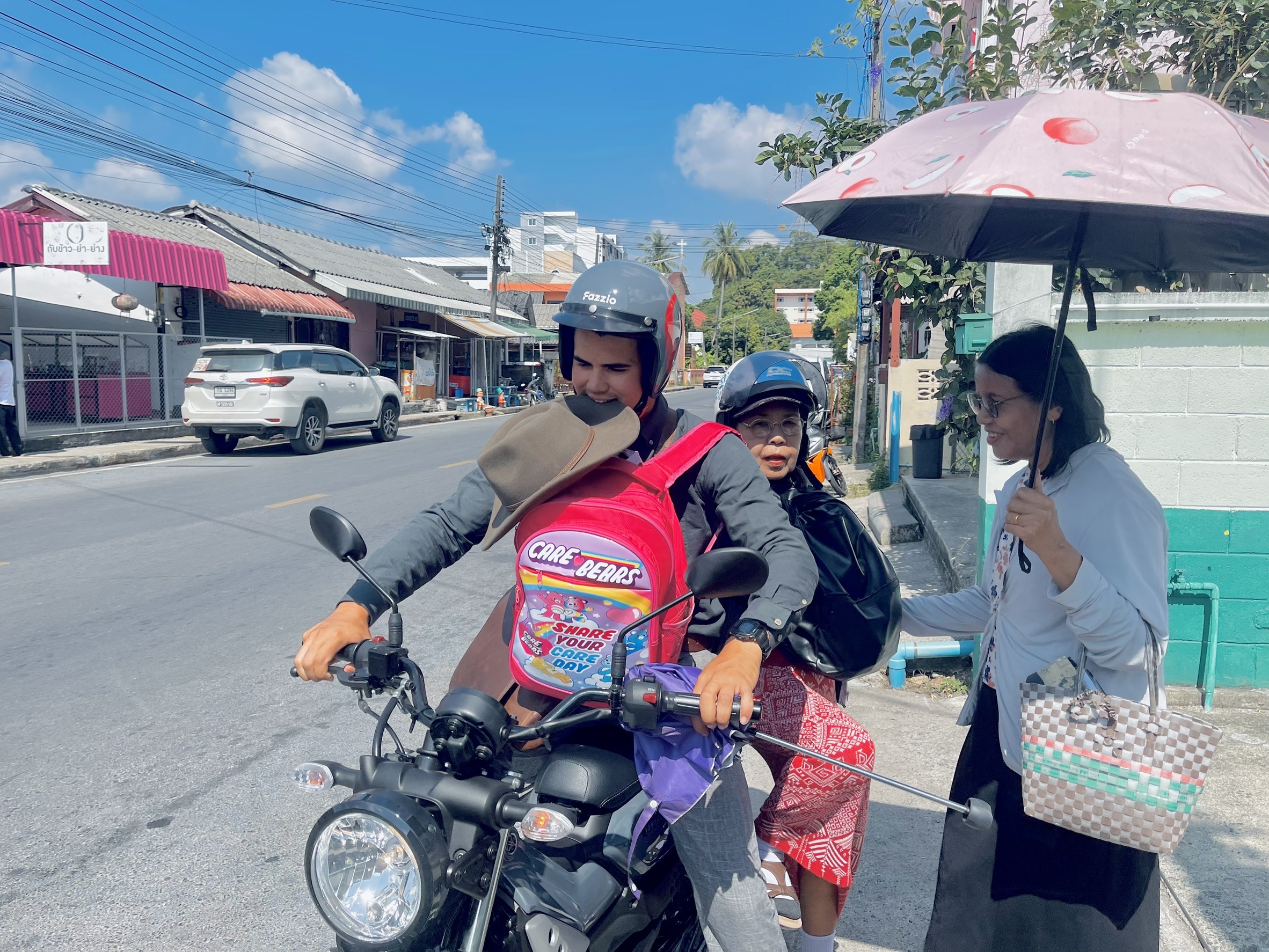 Friends gathering around a motorbike on a bright day in town