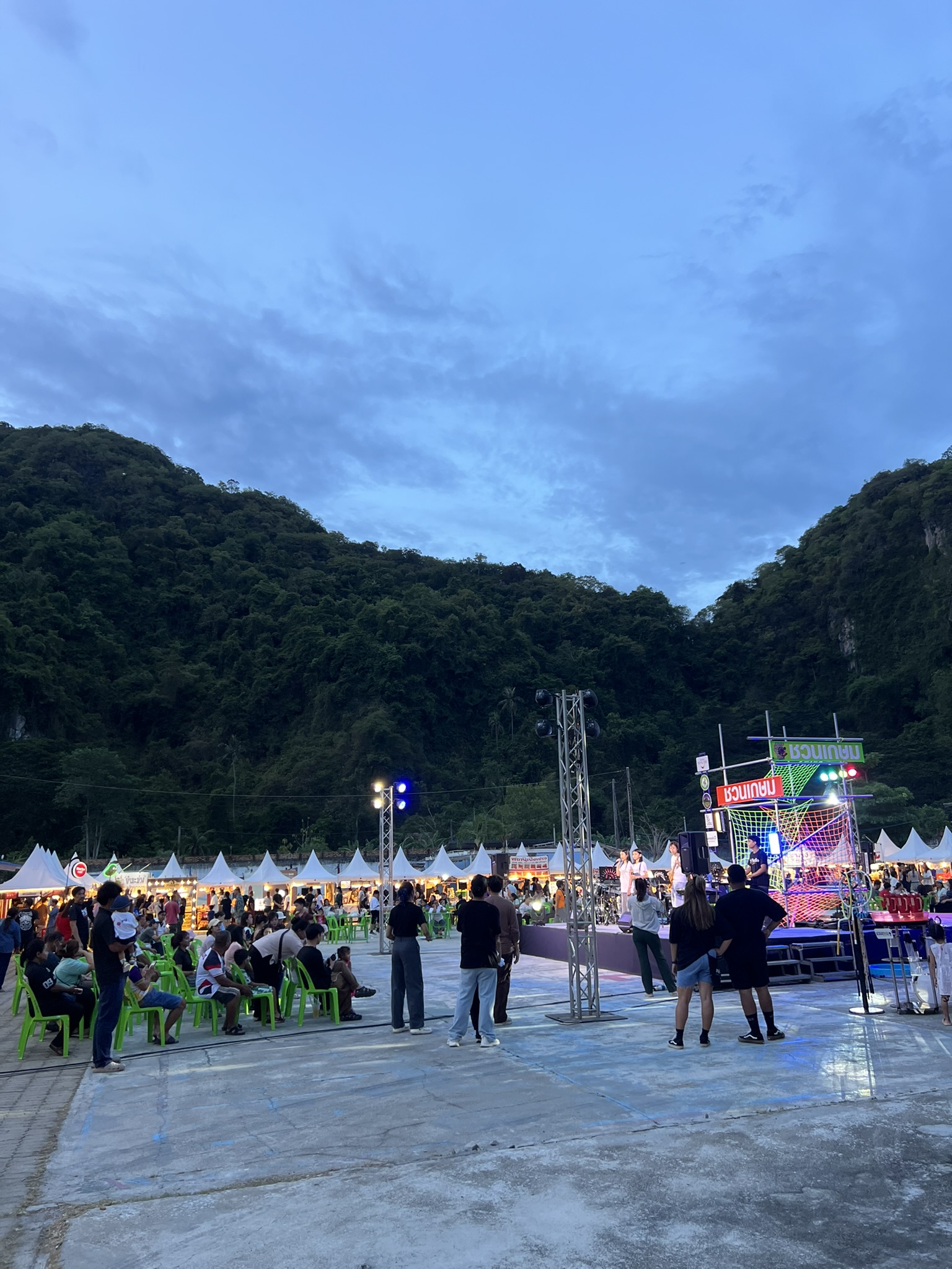 An evening market and live event beneath Phatthalung limestone hills
