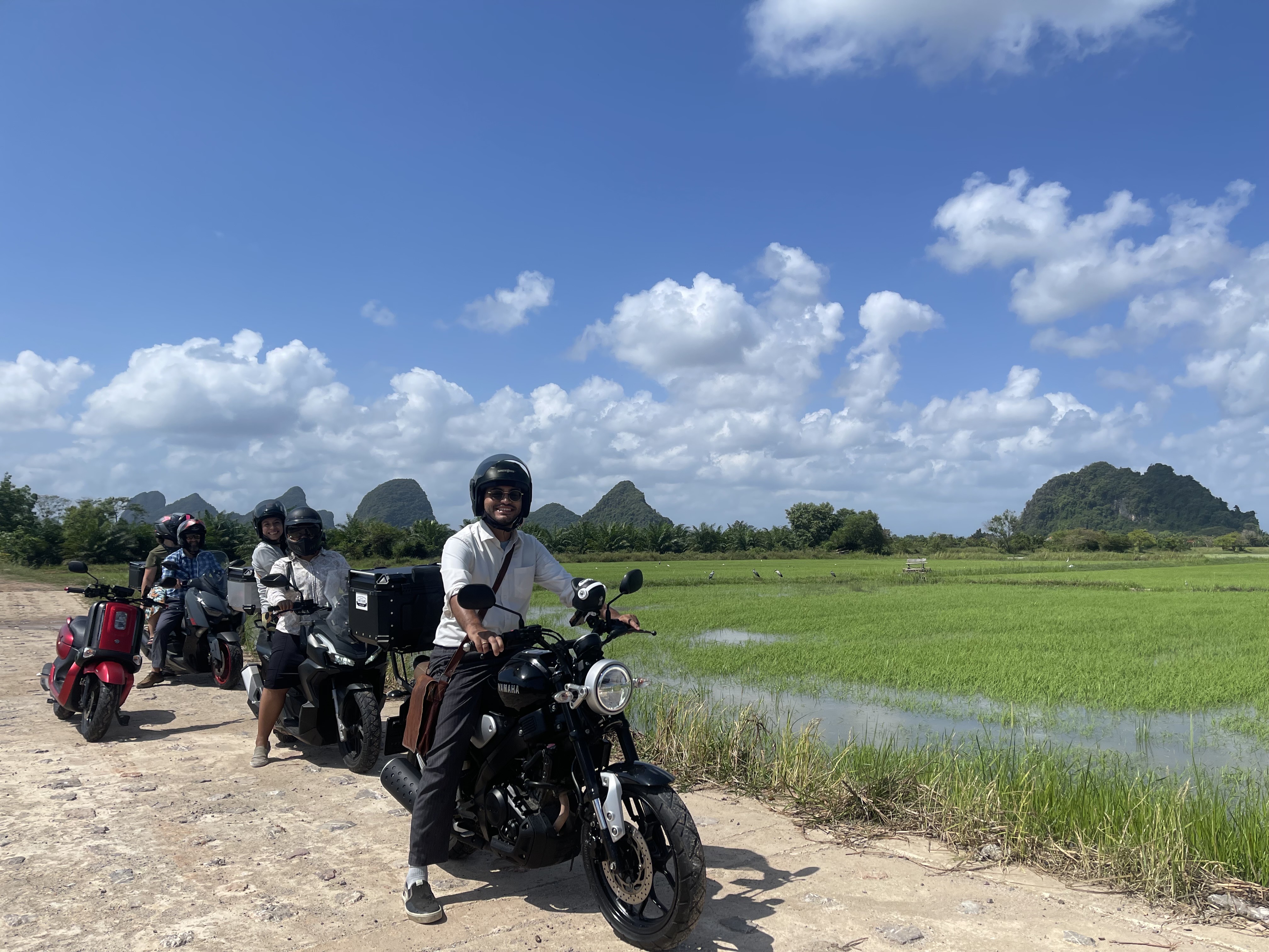 Friends pausing together on motorbikes beside vivid green rice fields