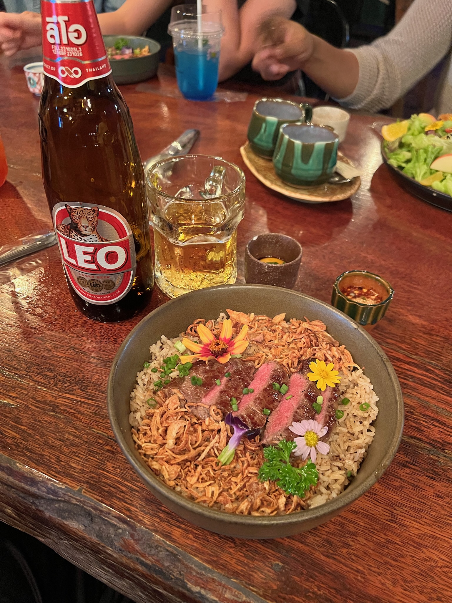 Steak over rice with a cold drink shared at dinner
