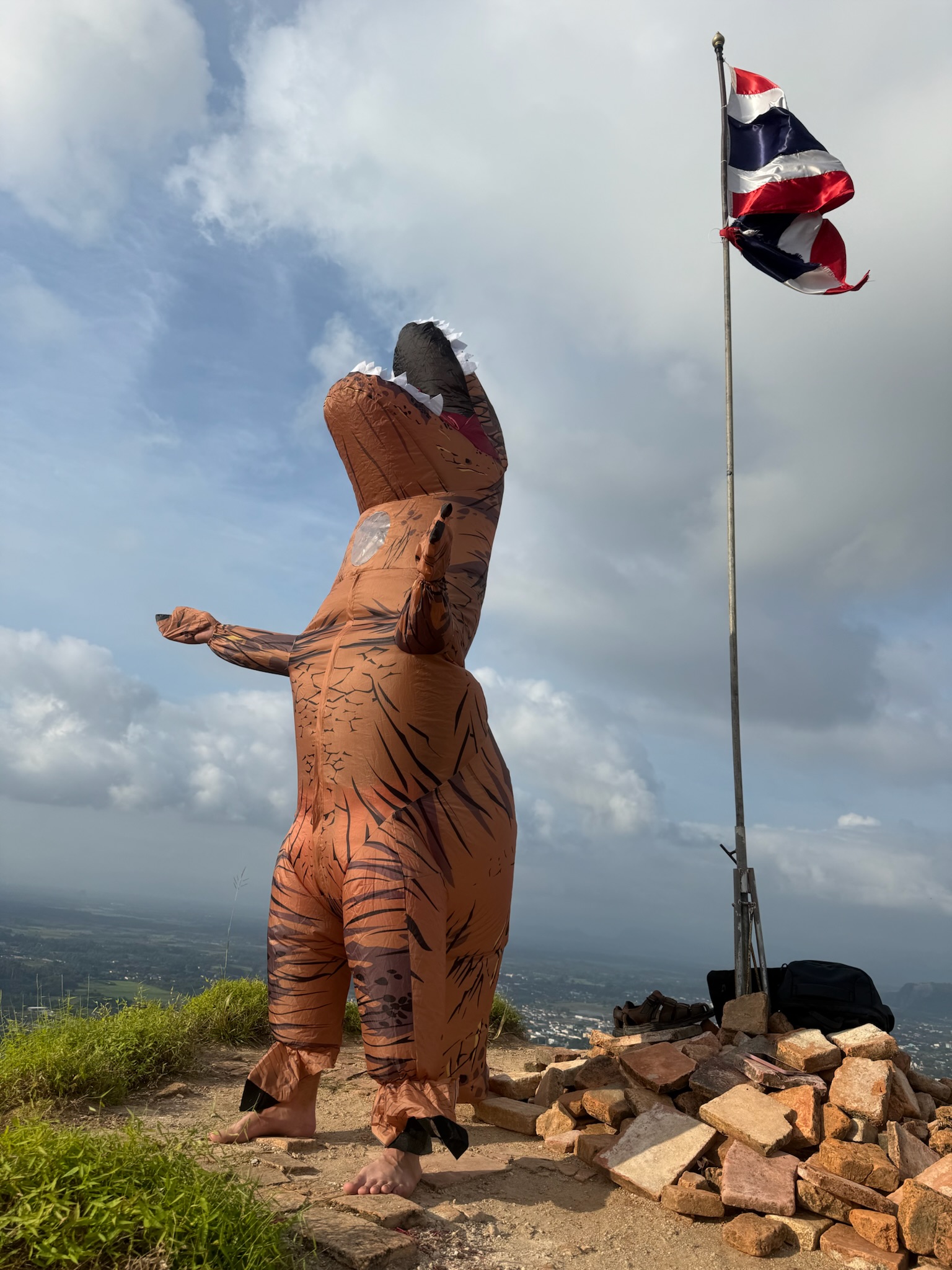 A playful dinosaur costume at a Phatthalung mountain summit