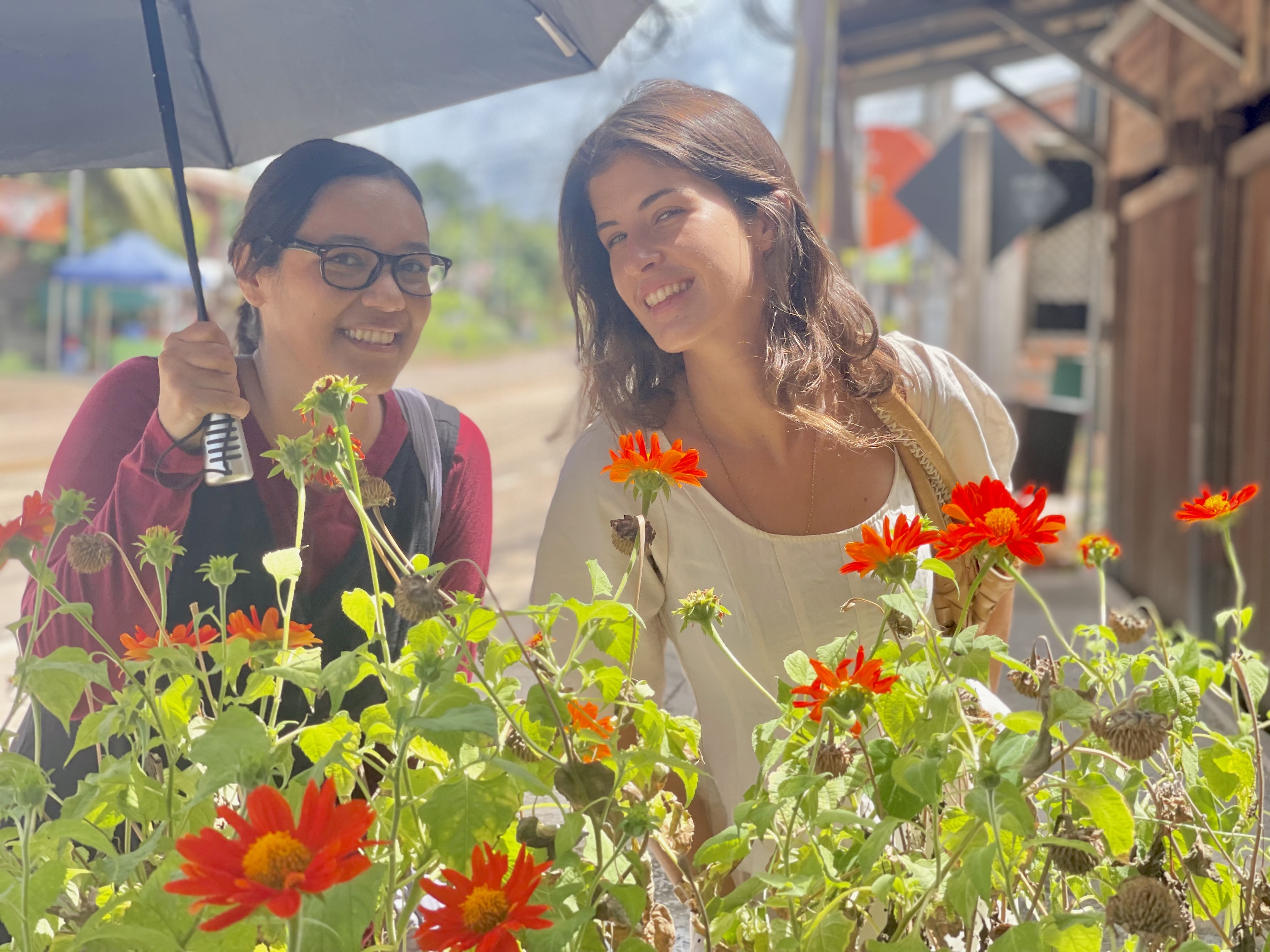 Two friends smiling together among bright orange flowers