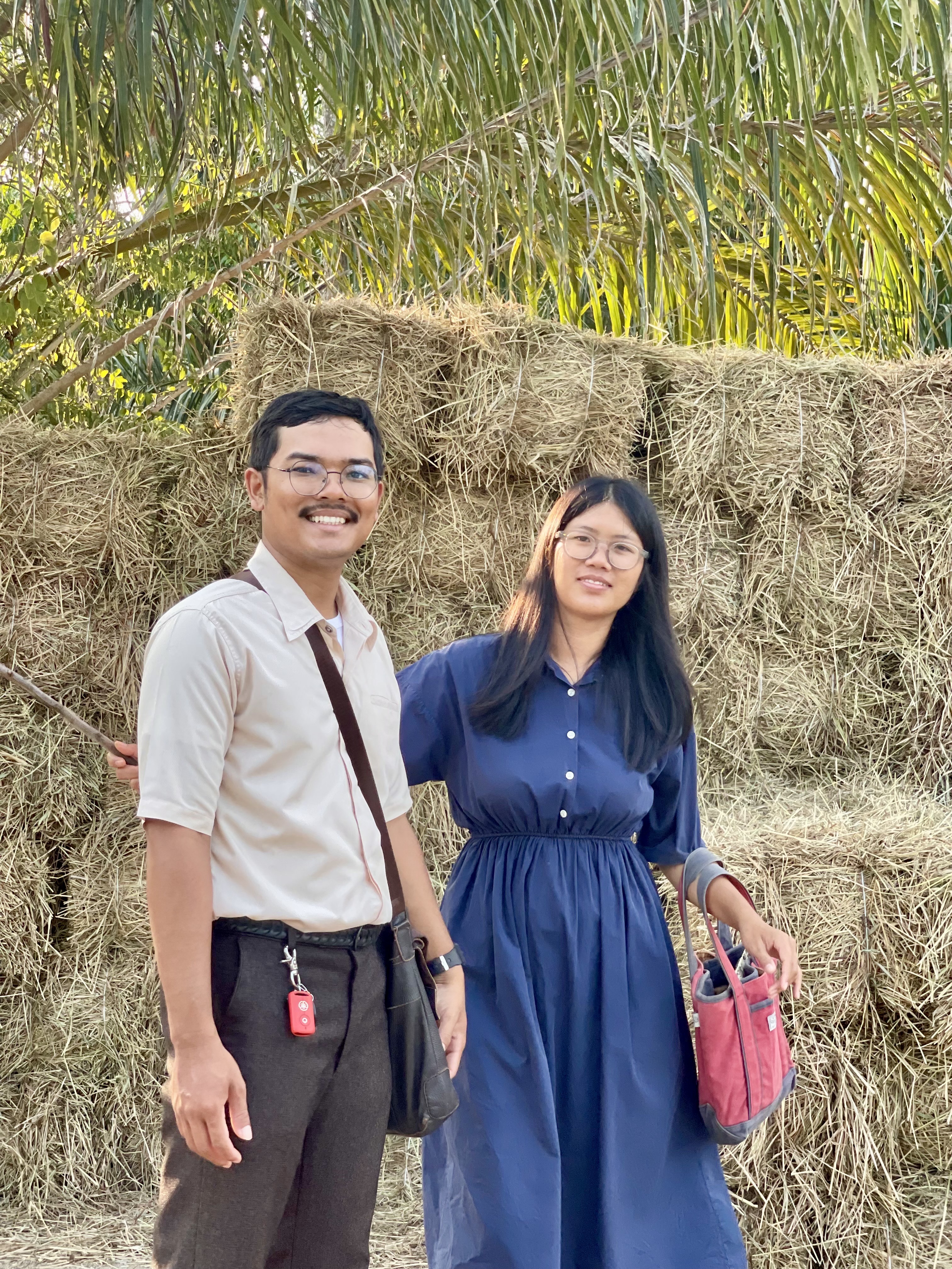 Two congregation friends smiling beside a haystack