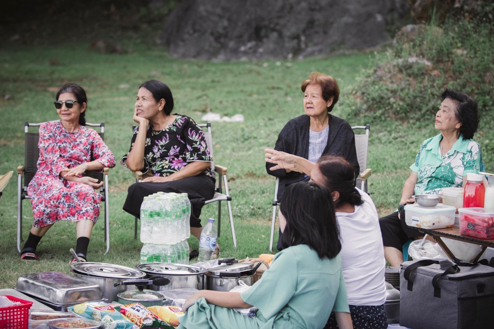 Older congregation friends talking together beside an outdoor picnic table