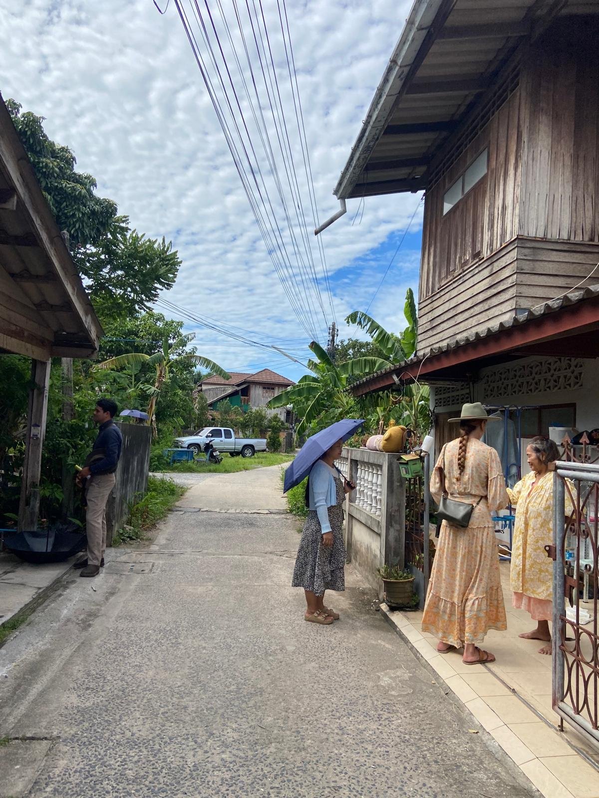 Friends visiting with a neighbor along a quiet village lane