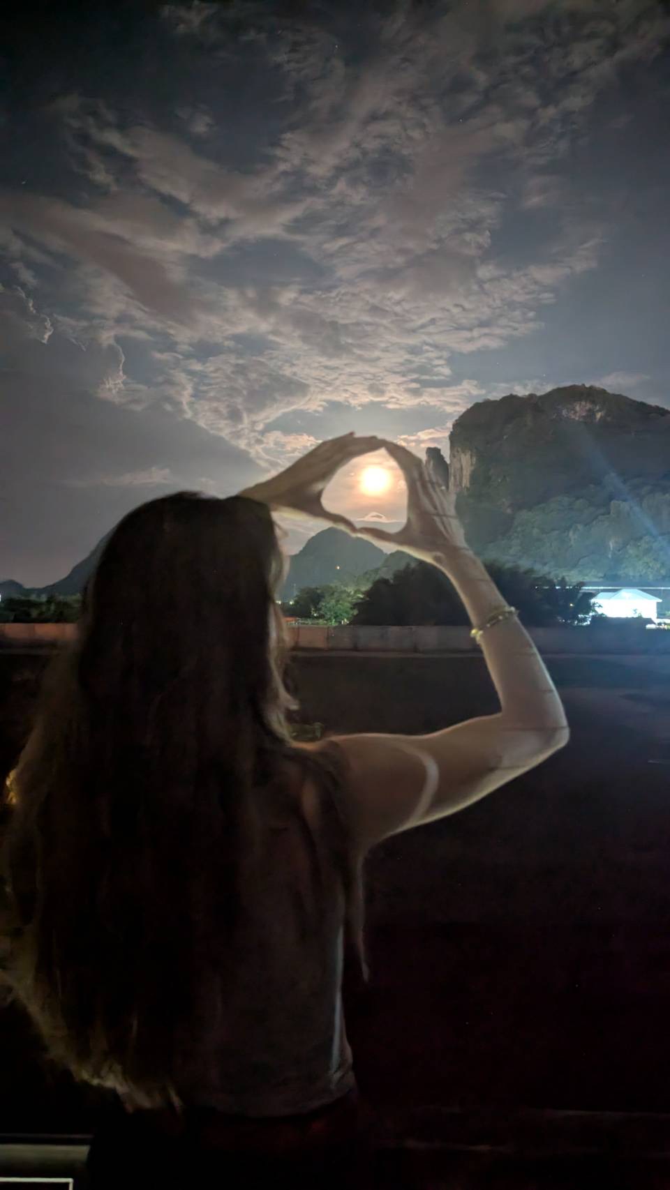 A friend framing the moon above a Phatthalung mountain