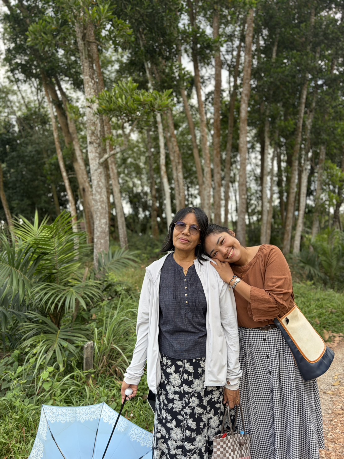 Two friends leaning close together on a green forest path