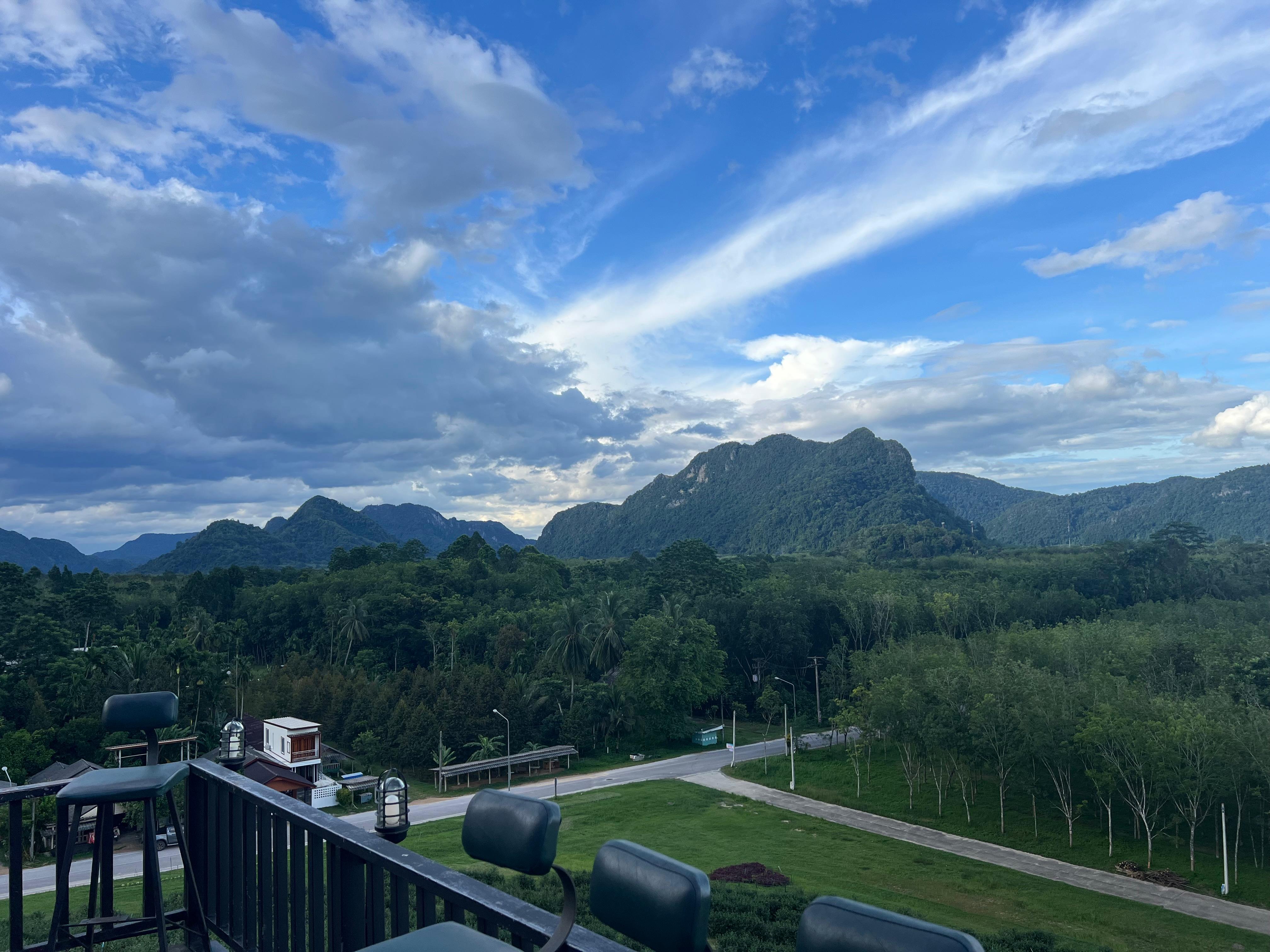 A wide view of forested Phatthalung mountains beneath a dramatic blue sky