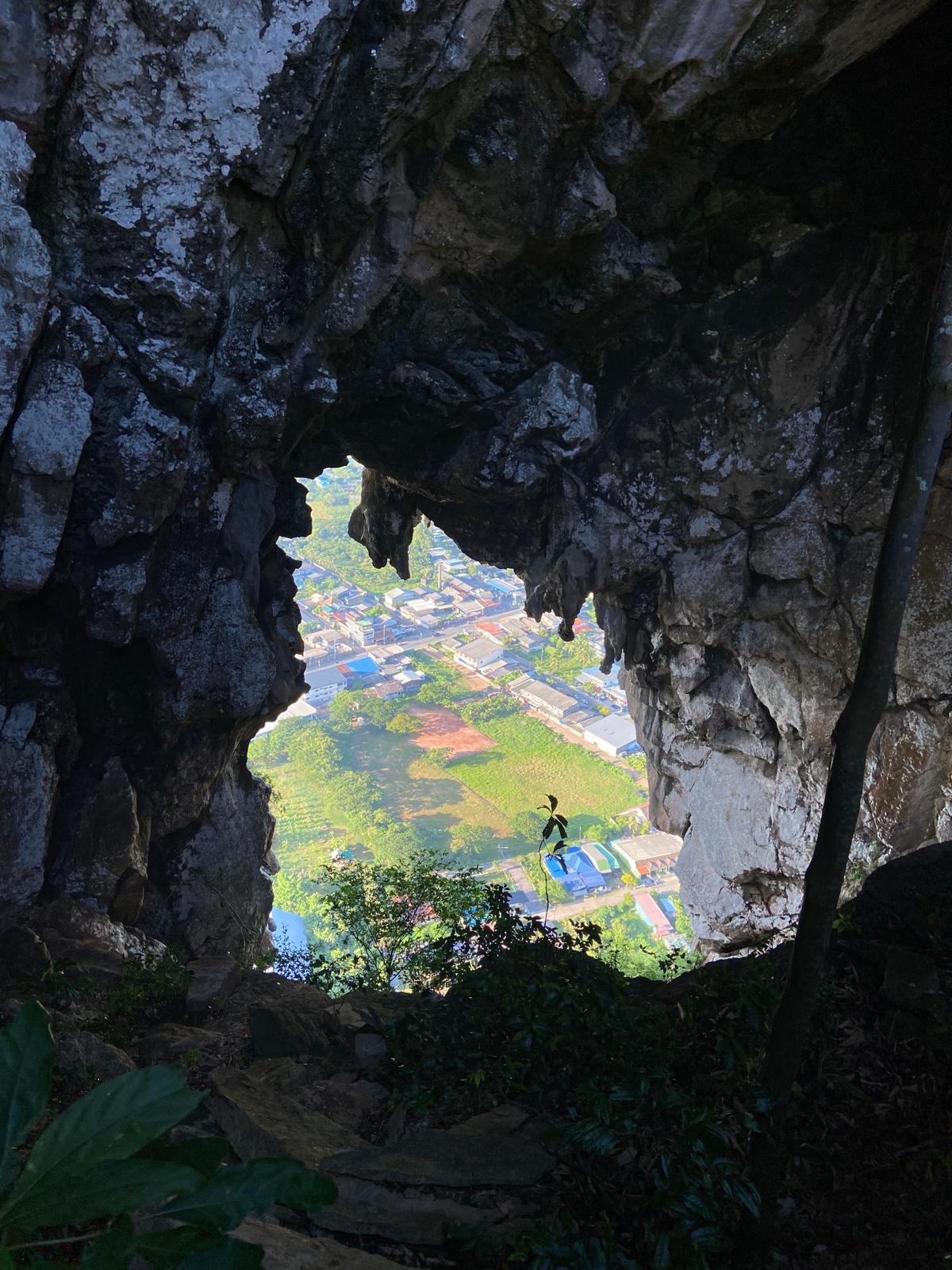A cave opening framing a high view over Phatthalung town